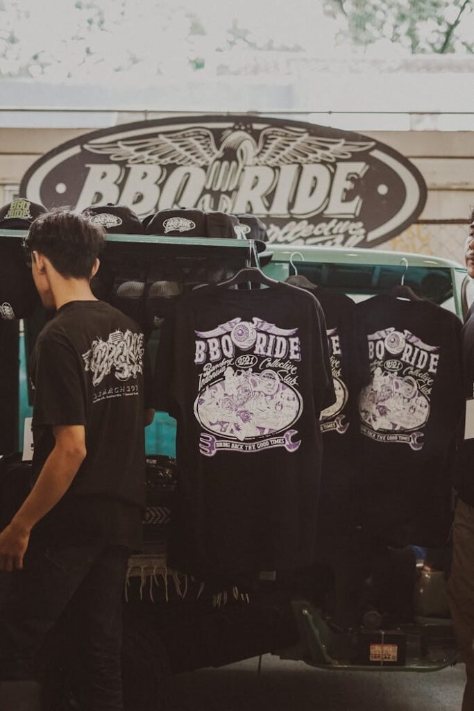 pexels-photo-12879454 Street vendor displaying BBQ Ride shirts at a casual outdoor market.